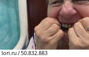 A woman carefully removes her denture after a long day, gently cleaning it with care to keep it in good condition for her daily use. Стоковое видео, видеограф Ирина Старикова / Фотобанк Лори
