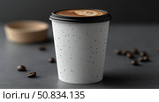 Morning drink: A latte cup with frothy art on a grey table with dark roasted arabica seed. Стоковое AI-изображение, AI-художник Данила Большаков / Фотобанк Лори