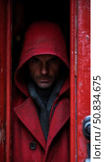 Intense Gaze: A mysterious hooded man peers from behind a vibrant crimson doorway, adding suspense. Стоковое AI-изображение, AI-художник Данила Большаков / Фотобанк Лори