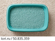 Cat litter box filled with white-gray litter with blue particles. Clumping cat in home background. Clean teal blue pet litter box placed on a rug carpet. Cleanliness concept. Cat toilet. Pets hygiene. Стоковое AI-изображение, AI-художник Марина Демидюк / Фотобанк Лори