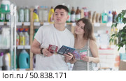 Married couple stands in the household section of a supermarket and chooses a set of razors for every day. Buyers consider the packaging of razors from different manufacturers. Стоковое видео, видеограф Яков Филимонов / Фотобанк Лори