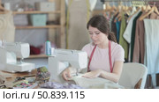 Young seamstress working on modern sewing machine in sewing workshop. Стоковое видео, видеограф Яков Филимонов / Фотобанк Лори