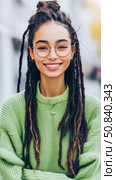Portrait of a cheerful young woman with dreadlocks and glasses smiling brightly, exuding joy and confidence. Стоковое AI-изображение, AI-художник Данила Большаков / Фотобанк Лори