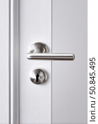 Close-up of modern stainless steel door handle and keyhole on a white wooden door, symbolizing security, privacy, and home design. Стоковое AI-изображение, AI-художник Катерина Бондарец / Фотобанк Лори