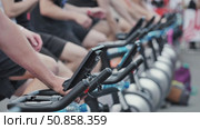 Athletes pedaling stationary bikes during sports day competition. Стоковое видео, видеограф Mikhail Davidovich / Фотобанк Лори