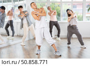 Young man standing performs basic hip hop movements in front of group of students. Стоковое фото, фотограф Яков Филимонов / Фотобанк Лори