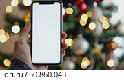 Close up black smartphone with blank screen in woman hand. Digital phone mock up. Christmas online shopping. Mobile phone with empty screen on background of Christmas tree lights. Tablet. Copy space. Стоковое AI-видео, аниматор Марина Демидюк / Фотобанк Лори