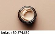 Creamy moisturizer in a glass jar on a neutral background. Стоковое AI-изображение, AI-художник Katsiaryna Repich / Фотобанк Лори