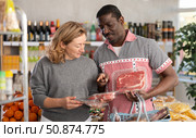 African man and European wife in store took raw beef steaks and hamburger cutlet, choose meat ware. Стоковое фото, фотограф Яков Филимонов / Фотобанк Лори