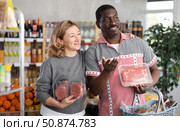 African man and European wife in store took raw beef steaks and hamburger cutlet, choose meat ware. Стоковое фото, фотограф Яков Филимонов / Фотобанк Лори