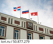 The top of the Perm city administration building with the city's coat of arms, the flags of Russia, the Perm Region and the city of Perm. Редакционное фото, фотограф Бузмакова Светлана / Фотобанк Лори