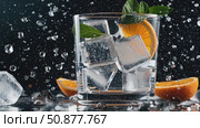 Sparkling ice cubes clinking, vibrant orange wedge nestled near fresh mint, cool beverage resting on dark surface with glistening condensation droplets. Стоковое AI-видео, аниматор Данил Руденко / Фотобанк Лори