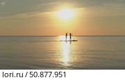 Couple paddle boarding at golden sunset. Стоковое видео, видеограф Андрей Знаменский / Фотобанк Лори
