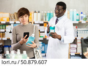 Woman buyer scans mouthwash qr code with woman pharmacist. Стоковое фото, фотограф Яков Филимонов / Фотобанк Лори