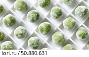 Frozen green fruit arranged neatly in ice tray compartments during winter. Стоковое AI-изображение, AI-художник Katsiaryna Repich / Фотобанк Лори