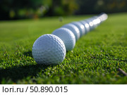Row of golf balls lying on lush green grass of driving range. Стоковое AI-изображение, AI-художник Иван Рябоконь / Фотобанк Лори