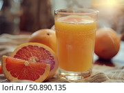 Glass of fresh grapefruit juice with ripe grapefruits on table. Стоковое AI-изображение, AI-художник Иван Рябоконь / Фотобанк Лори