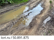 The dirt road is filled with muddy puddles after a rain. Concept of off-road. Стоковое фото, фотограф Ольга Петрова-Апостолова / Фотобанк Лори