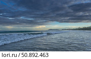 Morning seascape. The ocean waves roll towards the shore, foam and spread over the beach. Blue clouds. The sky at the horizon is highlighted in golden. Malaysia. Borneo. Kota Kinabalu. Стоковое фото, фотограф Вера Ивановна Кубарева / Фотобанк Лори