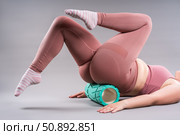 Fat woman in sportswear use myofascial release massage mfr roll on gray background, pelvic floor muscle exercise. Стоковое фото, фотограф Станислав Тарко / Фотобанк Лори