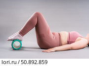 Fat woman in sportswear use myofascial release massage mfr roll on gray background, pelvic floor muscle exercise. Стоковое фото, фотограф Станислав Тарко / Фотобанк Лори