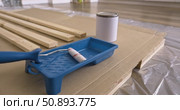 Painting tools and wooden planks prepared for home renovation, blue roller tray, paint can and pine boards neatly arranged on cardboard and protective film, DIY workspace, renovation, painting shelf. Стоковое видео, видеограф Сергей Тимофеев / Фотобанк Лори