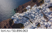 Aerial view capturing white washed Santorini buildings perched on volcanic cliffs, overlooking turquoise Aegean waters beneath dramatic landscape. Стоковое AI-видео, аниматор Данил Руденко / Фотобанк Лори