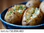 Baked potatoes with parsley resting in blue bowl. Стоковое AI-изображение, AI-художник Иван Рябоконь / Фотобанк Лори