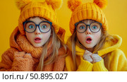 Surprised Girls with Pom-Pom Hats: Whimsical Portrait of Sisters in Autumn Colors, Fun and Cozy Fashion Statement. Стоковое AI-изображение, AI-художник Данила Большаков / Фотобанк Лори