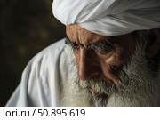 Senior muslim man wearing traditional clothing and praying. Стоковое AI-изображение, AI-художник Иван Рябоконь / Фотобанк Лори