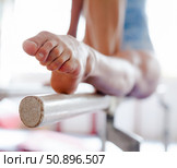 Pointed toes of female gymnast holding position on bars. Стоковое фото, фотограф Татьяна Яцевич / Фотобанк Лори