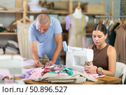 Young woman sewing, male assistant attaching template to fabric. Стоковое фото, фотограф Яков Филимонов / Фотобанк Лори
