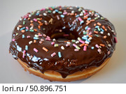Delicious chocolate donut covered with colorful sprinkles on white background. Стоковое AI-изображение, AI-художник Иван Рябоконь / Фотобанк Лори