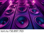 Many loudspeakers with purple and blue lighting playing music. Стоковое AI-изображение, AI-художник Иван Рябоконь / Фотобанк Лори