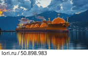 A majestic liquefied natural gas carrier glowing warmly on tranquil waters at dusk, reflecting vibrant illumination against a dramatic mountain backdrop. Стоковое AI-видео, аниматор Данила Большаков / Фотобанк Лори