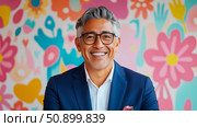 Portrait of a Smiling Man with Graying Hair Against a Floral Backdrop. Стоковое AI-изображение, AI-художник Данила Большаков / Фотобанк Лори