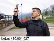 A man records videos on his phone and takes photos, tourist, traveler, blog content. Стоковое фото, фотограф Наталья Угрюмова / Фотобанк Лори