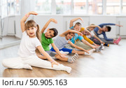 Little school age children learn to do dance moves on the floor in choreography studio. Стоковое фото, фотограф Яков Филимонов / Фотобанк Лори