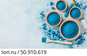 Beauty Product Still Life: Composition of Blue Spirulina Powder and Cosmetic Applicators on Light Blue Backdrop. Стоковое AI-изображение, AI-художник Данила Большаков / Фотобанк Лори