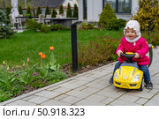 Spring Joyride: Little Girl's Garden Adventure on Toy Car. Стоковое фото, фотограф Данила Большаков / Фотобанк Лори