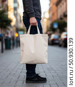 A man is holding a white canvas bag on a city street. Стоковое AI-изображение, AI-художник Ярославский Максим / Фотобанк Лори