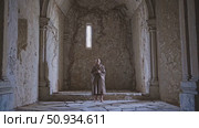 Serene monk praying inside crumbling chapel, weathered stone walls overgrown with climbing vegetation, reflecting contemplative stillness and spiritual meditation. Стоковое AI-видео, аниматор Данил Руденко / Фотобанк Лори