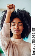 Empowerment concept: Portrait of a woman with fist raised in solidarity, eyes closed. Стоковое AI-изображение, AI-художник Данила Большаков / Фотобанк Лори