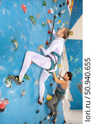 Focused woman climbing on bouldering wall with safety rope. Стоковое фото, фотограф Яков Филимонов / Фотобанк Лори