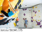 Bouldering, people and healthy lifestyle concept - young woman exercising at climbing gym. Стоковое фото, фотограф Яков Филимонов / Фотобанк Лори