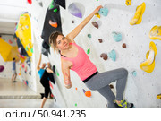 Woman showing thumb up while exercising on artificial climbing wall. Стоковое фото, фотограф Яков Филимонов / Фотобанк Лори