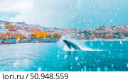 Whale breaching in tranquil turquoise waters facing a coastal settlement. Стоковое AI-изображение, AI-художник Данила Большаков / Фотобанк Лори