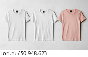 Three neatly arranged short-sleeve crewneck T-shirts, two white and one pink, displayed for clothing retail or print, advertising purposes. Стоковое AI-изображение, AI-художник Данила Большаков / Фотобанк Лори