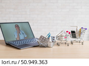 Online medicine and pharmacy concept. A female doctor conducts an online consultation and recommends medications. Mini trolley with tablets at the laptop. Стоковое фото, фотограф Михаил Решетников / Фотобанк Лори