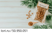 Healthy Pet Nutrition: Top-down presentation of premium dog kibble in a pouch, with a wooden spoon and treats, framed by green tropical foliage on a light wood surface, ideal for product display. Стоковое AI-изображение, AI-художник Данила Большаков / Фотобанк Лори